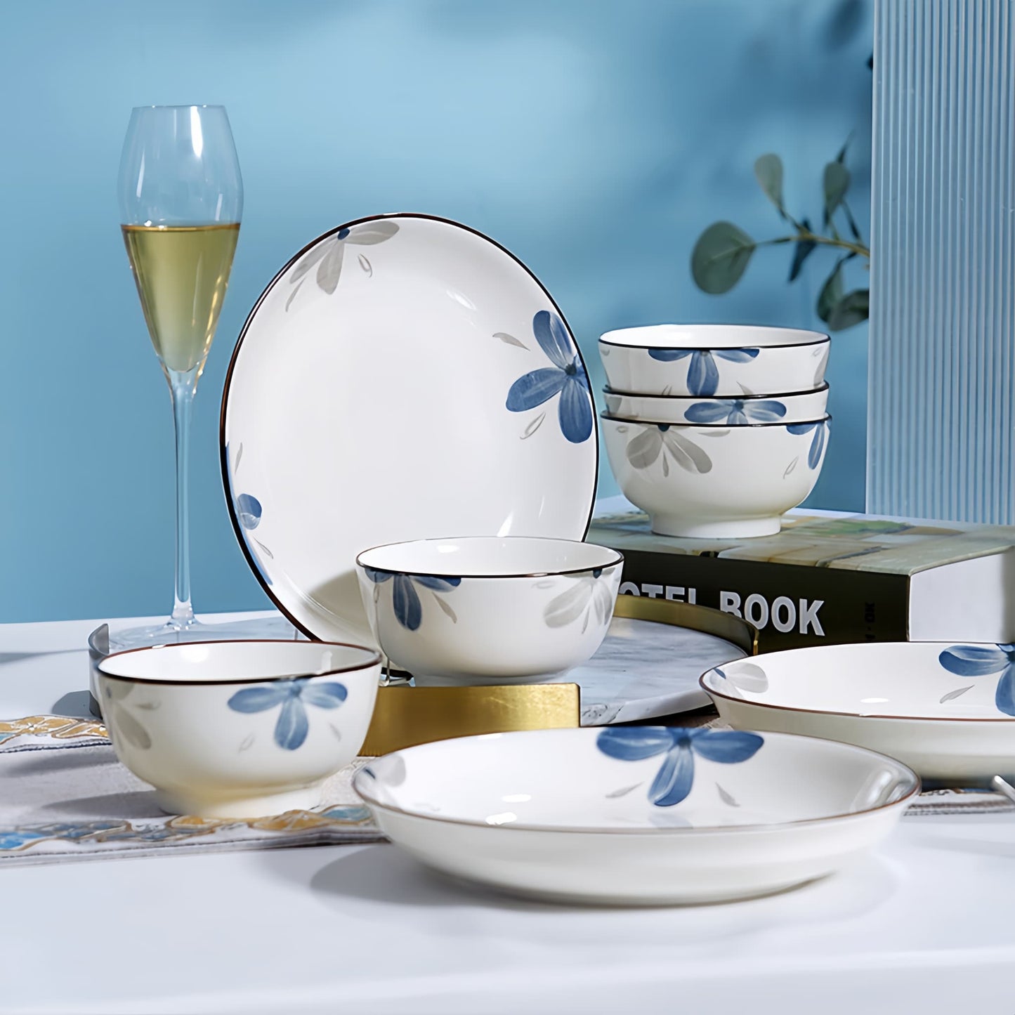 Ceramic dinnerware set with blue floral patterns on a table against a blue wall. YUNGPING Azure Future Everyday Ceramic Dinnerware Set, 10-Piece