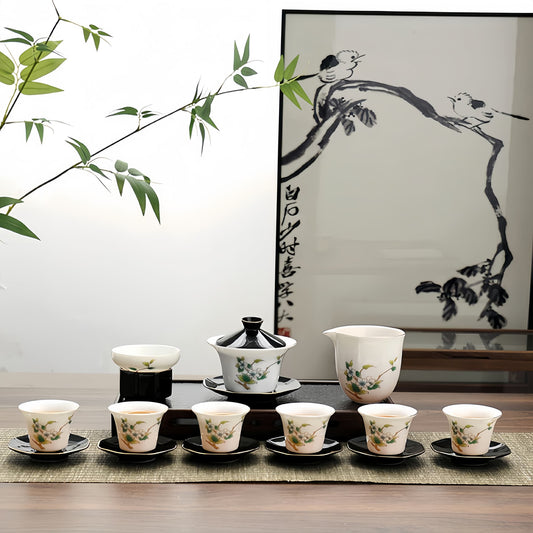 Tea set with ceramic cups and teapot on a wooden table, framed by a branch with leaves. YUNGPING Camellia Jade Cream Porcelain Gaiwan, 16-Piece