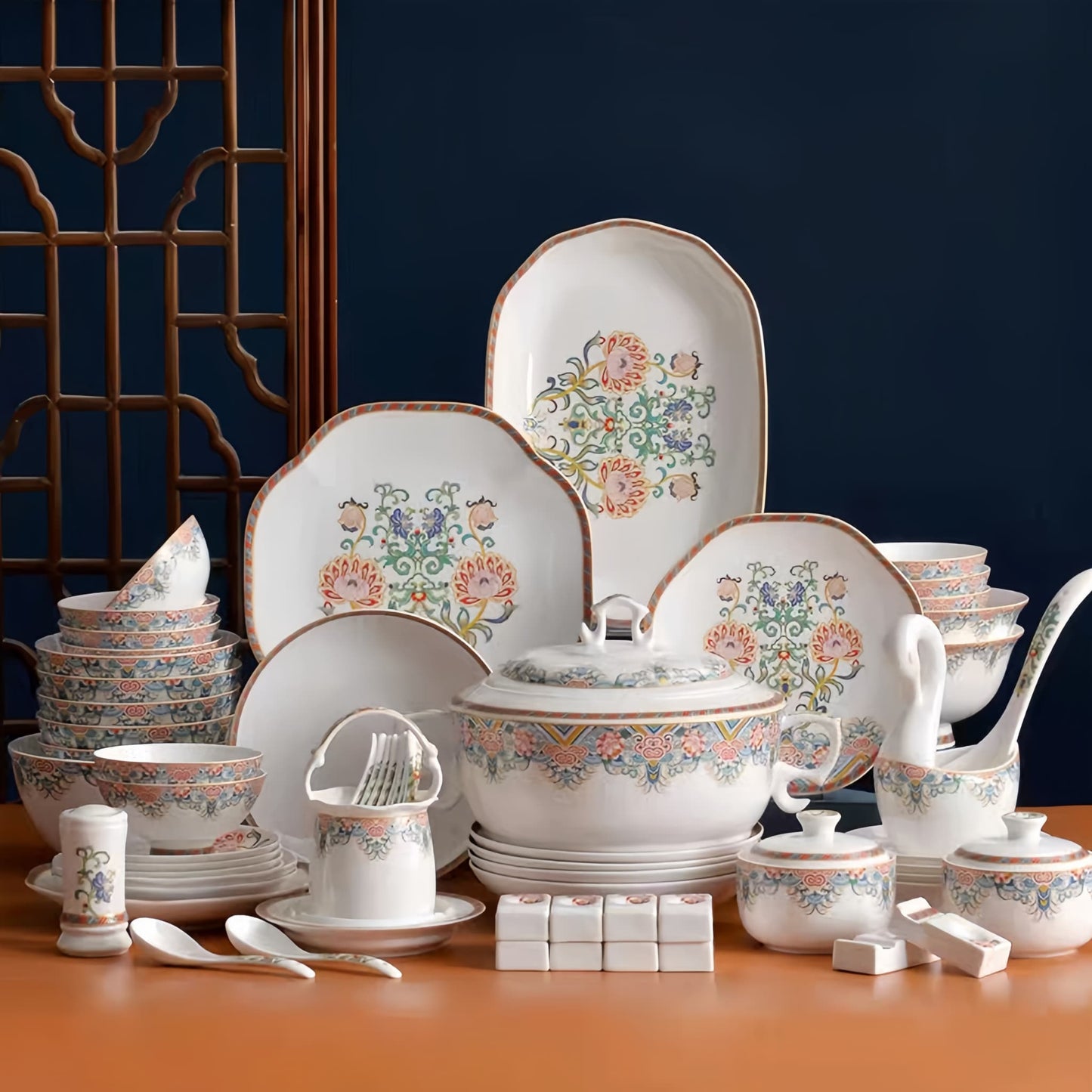 Dishware set with floral patterns on a wooden table against a dark blue wall. YUNGPING Brocade Floral Cluster Fine Bone China Dinnerware Set, 69-Piece, styled on an elegant dining table for formal hosting and special occasions.
