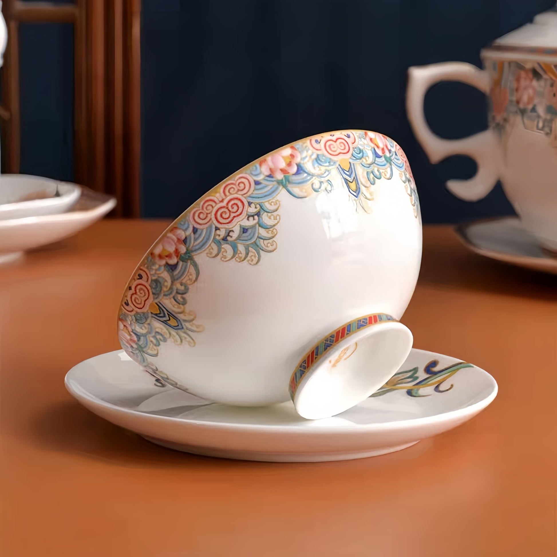 Decorative teacup and saucer with floral patterns on a wooden table. YUNGPING Brocade Floral Cluster Fine Bone China Dinnerware Set, Close-up detail