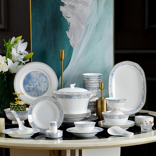 Dinnerware set with blue floral patterns on a table against an abstract painting background, YUNGPING Cerulean Spirit Fine Bone China Dinnerware Set, 50-Piece, styled on an elegant dining table for formal hosting and special occasions.