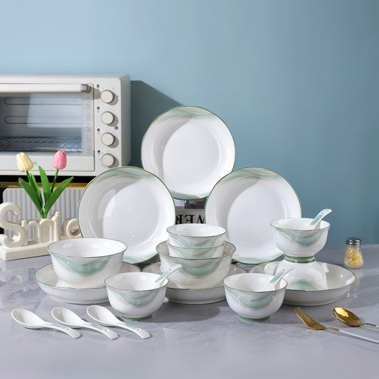 Dinner set with green and white patterns on a table with kitchen appliances in the background. YUNGPING Cyan Memory Everyday Ceramic Dinnerware Set, 20-Piec
