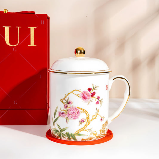 Decorative mug with floral design next to a red gift box on a light background, YUNGPING Delicate Blossom Fine Bone China Lid Cup, 3-Piece, styled for a casual afternoon tea.