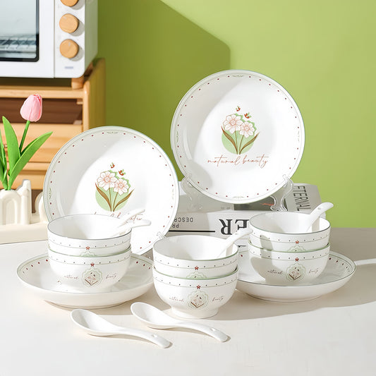 Set of ceramic dishes with floral designs on a white surface against a green wall. 