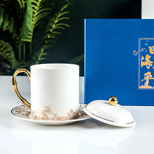 White mug with gold accents and matching lid on a saucer, next to a blue gift box with gold text. YUNGPING Gilded Seas Fine Bone China Lid Cup, 3-Piece, styled for a casual afternoon tea setting.