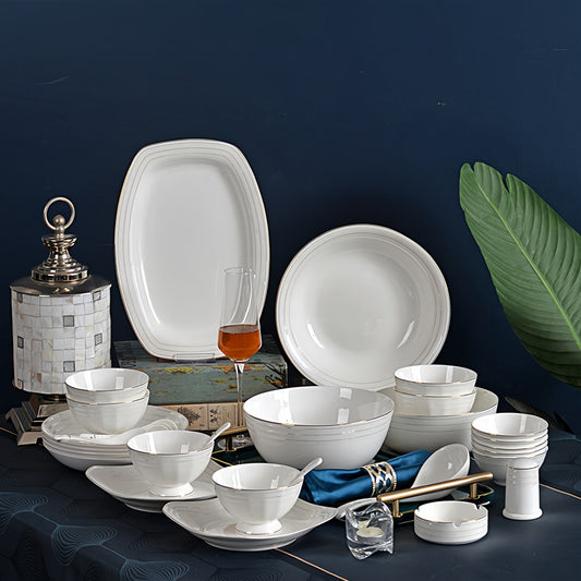 Set of white dinnerware on a dark surface with decorative elements. YUNGPING Iris Glow Fine Bone China Dinnerware Set, 33-Piece, styled on an elegant dining table for formal hosting and special occasions.