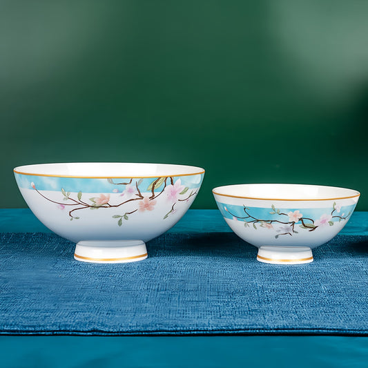 Two bone china bowls with floral designs on a blue surface against a green background, YUNGPING Peach Blossom Veil2  Dinnerware Set, Close-up detail