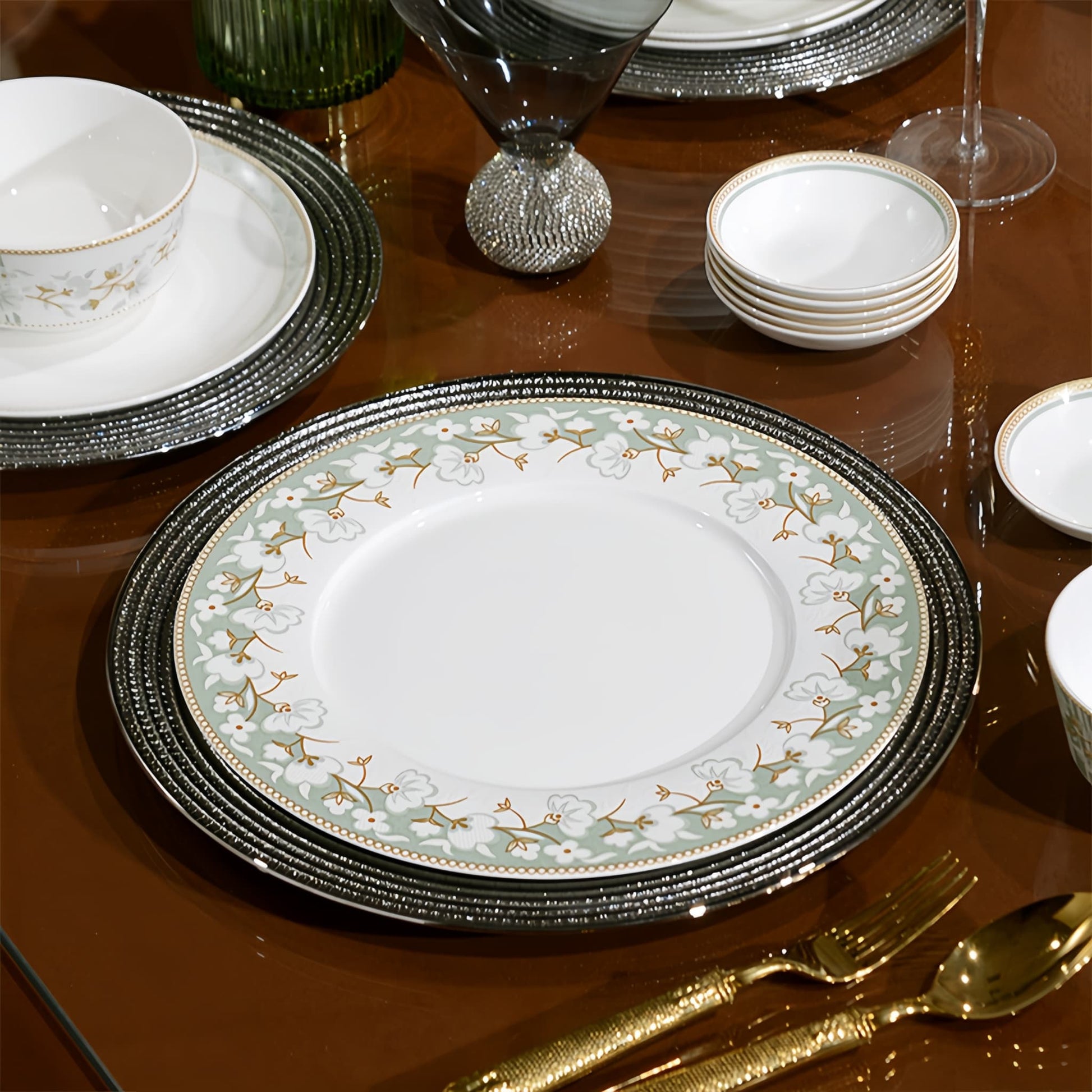 Decorative dinnerware set on a reflective surface with gold cutlery. YUNGPING Prairie Bloom Fine Bone China Dinnerware Set, Close-up detail